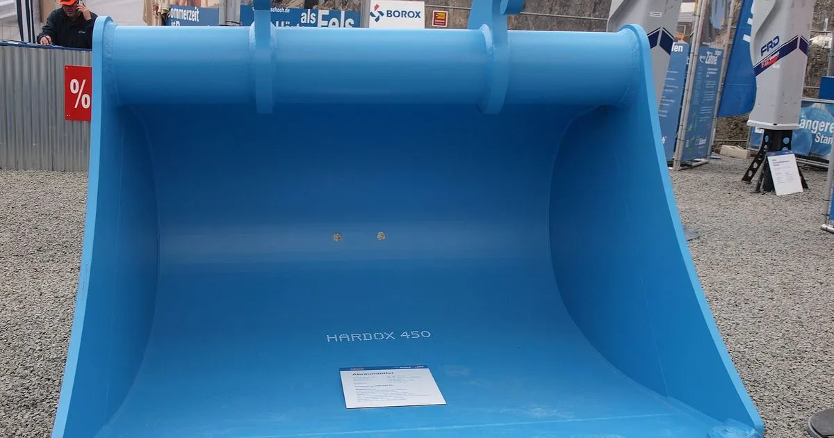 Blue excavator bucket marked Hardox 450 with replaceable teeth, an example of AR400 class wear plate fabrication