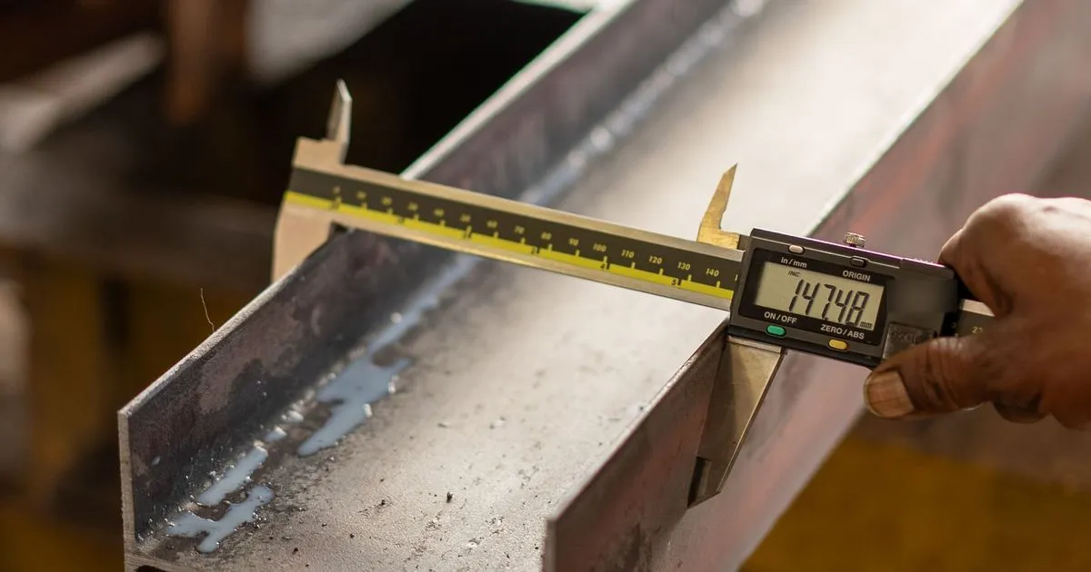 Digital caliper measuring the flange of a steel I-beam, a receiving check made alongside EN 10204 3.1 certificates