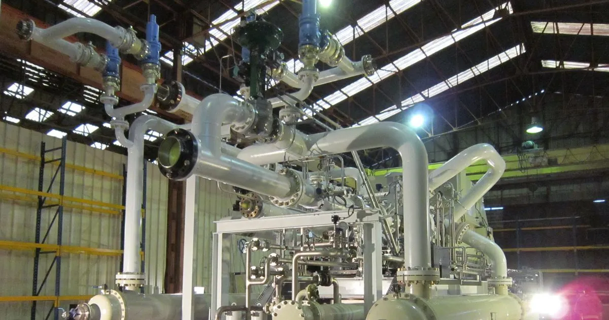 Centrifugal compressor package with piping mounted on a steel skid in a workshop, the kind of equipment carried by a compressor base frame