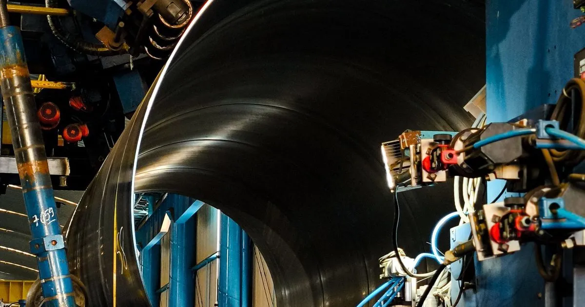 Large rolled steel cylinder inside a forming and welding machine, an example of heavy plate rolling fabrication