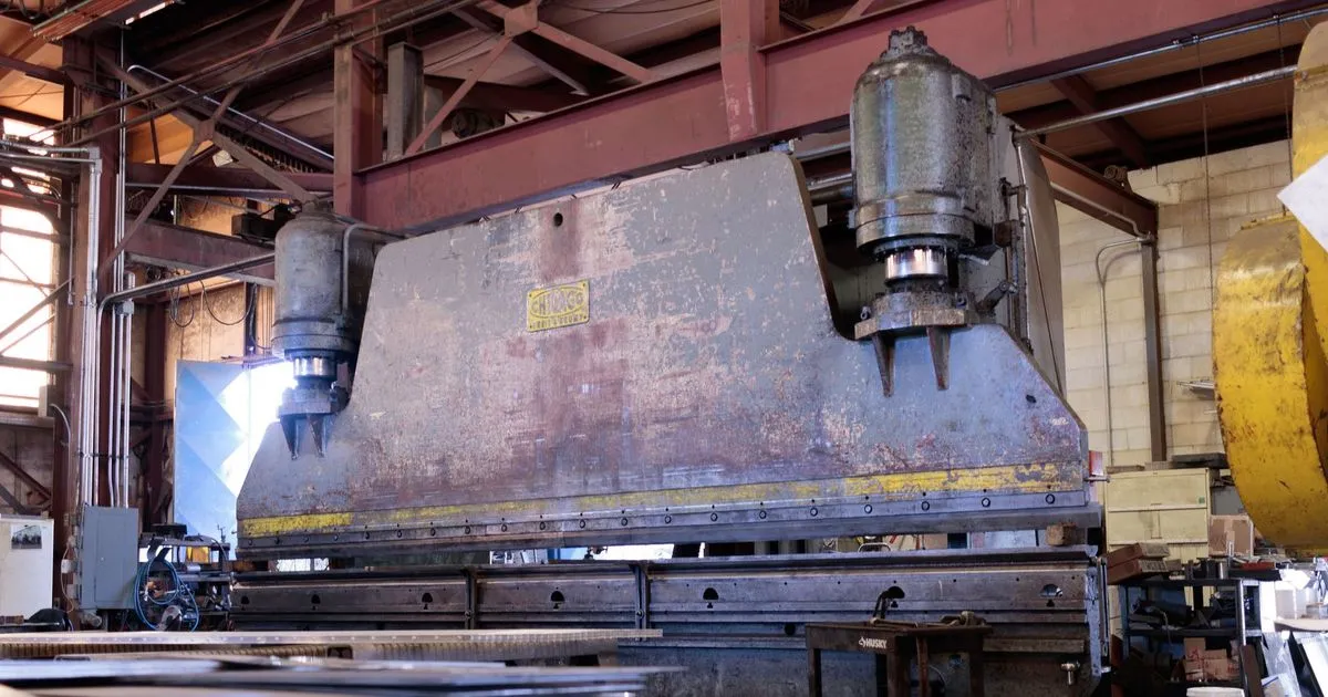 Large hydraulic press with a fabricated steel plate frame in a workshop, an example of hydraulic press frame fabrication