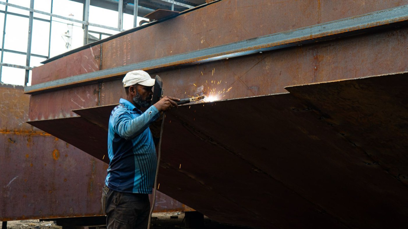 Welder working on a heavy plate steel structure in a fabrication yard